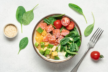 Salmon bowl with spinach, rice, avocado, tomato, cucumbers on a white background, top view. Poke bowl, healthy eating