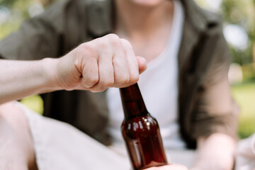 Closeup man hands opening beer bottle, enjoying picnic, selective focus