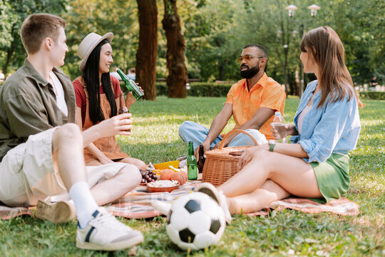 Group of diverse positive friends, meeting at birthday party, sitting in park picnic