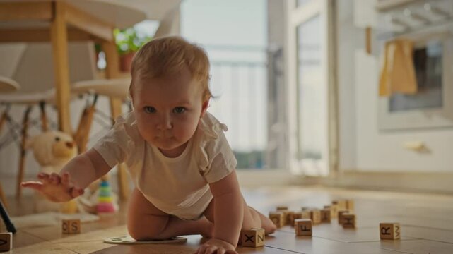 The baby makes his first independent movements, exploring the world around him. On a clear day, the child plays with toys, crawling on the floor in the kitchen