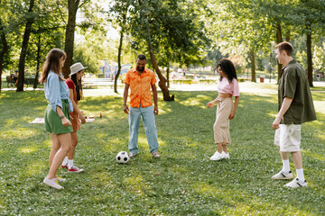 Fototapeta na wymiar Group of diverse, happy, multinational friends playing soccer in the park, free time, friendship concept