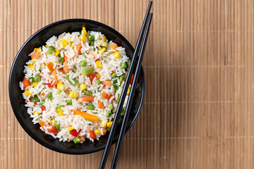White fried rice with vegetables on wooden table. Top view. Copy space