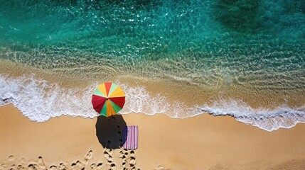 Obraz premium Footsteps leading from a beach umbrella and towel down to the edge, a classic beach day scene.