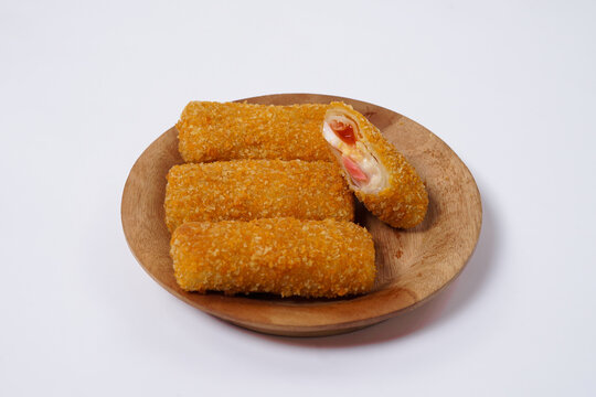 American Risoles or risoles mayo is a traditional Indonesian snack filled with smoked beef or sausage, boiled eggs & mayonnaise. Crispy texture on the outside. Risoles on wood plate isolated white.