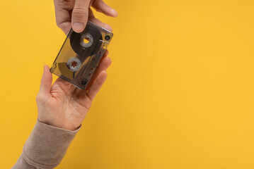 Closeup photo of woman passing vintage audio tape cassette to male hands. Flat lay of hands with an...