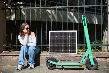 Woman using portable solar panel to charge electric scooter, emphasizing integration of sustainable...