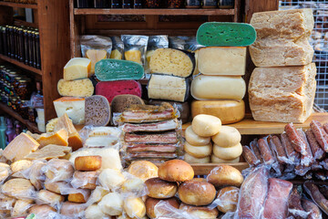 Craft cheeses on the counter of a farm shop. Multi-colored cheese wheels. Craft sausages, meat products. Eco-products. Delicacies. 