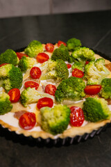 Pie Quiche Lorraine with broccoli, tomatoes and chicken fillet on the table close-up. Copy space.