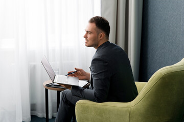 Young handsome businessman working with laptop in hotel room