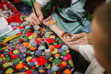 Woman  painting temporary tattoo with glitter on the child's hand