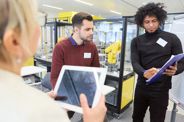 Team of engineers discussing robotics programming and automation in a modern tech lab