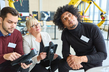 Group of engineers programming robotics in an industrial setting during a training session