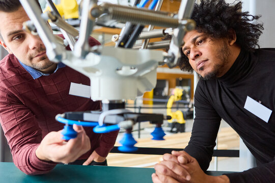 Engineers examining robotic gripper arm during industrial automation training session