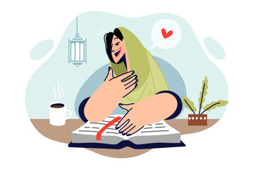 Islamic woman reads koran, sitting at table and studying religious muslim book, dressed in hijab