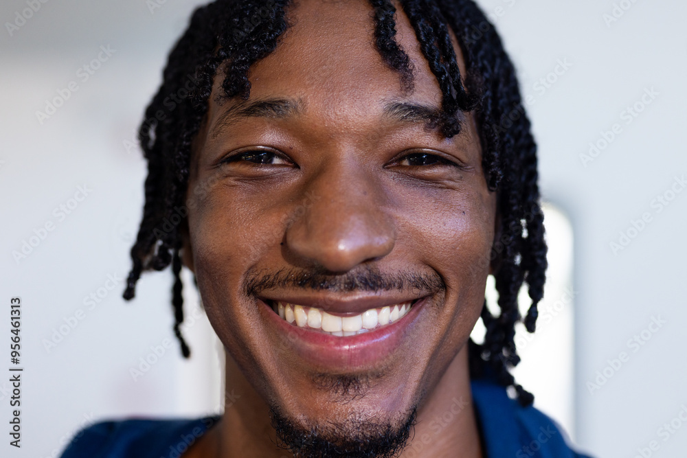 Wall mural Smiling african american man with braided hair looking at camera, close-up portrait