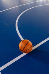 Fototapeta premium Basketball on court, resting on blue floor with white lines, copy space