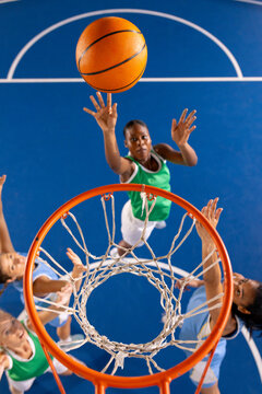 Playing basketball, women reaching for ball near hoop on court