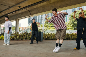 Group of young men breakdancing under urban bridge in North Seoul Park Brimming with energy, they...