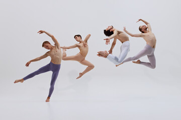 Dancers' synchronized leaps embody essence of creating art through intense physical training and dedication against white studio background. Concept of music, dance, modern and classical art, movement