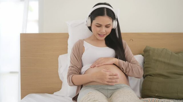 Happy pregnant woman with headphones listening to music