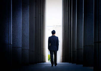 Obraz premium コンクリート壁の中を歩くビジネスマン