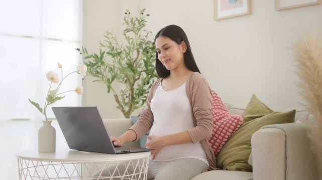 Pregnant woman working on laptop and smart phone in the living room at home