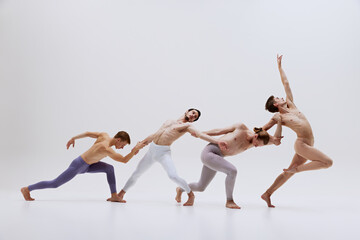 Obraz premium Dancers move in graceful sequence, emphasizing fluidity and connection as they stretch and reach towards each other, forming cohesive unit. Concept of music and dance, modern and classical art.