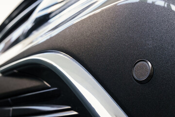 front parking sensor on a fender of modern car, proximity sensor to alert the driver of obstacles while parking, sensor on front bumper