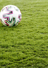  Green Artificial Grass with a Blurred Colourful Football in the Background