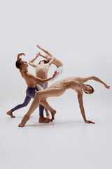 Fototapeta premium Balanced between control and freedom, ballet dancers' forms carve space with each movement against white studio background. Concept of music and dance, modern and classical art, movement.