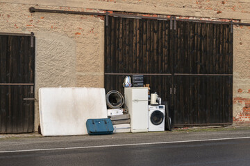 Elektromüll  und Matratzen stehen vor einem Scheunentor