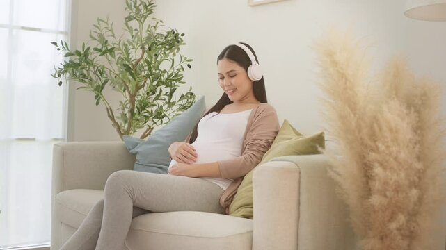 Happy pregnant woman with headphones listening to music
