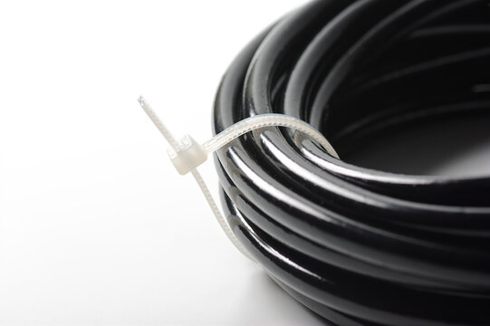 An image of a cable tie securing a small hose to keep it organized against a white background. A cable tie is a component used to bundle and secure items together