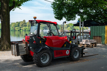 Compact red forklift parked near the waterfront in a busy area