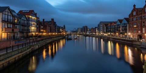 An urban riverfront scene at twilight, featuring modern and historic buildings with their lights reflecting on the calm river waters, creating a picturesque evening ambiance.