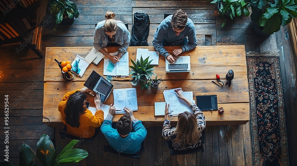 Fototapete a group of people are working together at a table with papers and laptops scene is collaborative and