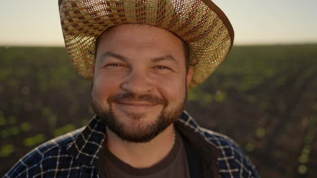 Closeup view of happy face of farmer man in beautiful cornfield in summer day. Portrait of successful farm owned, agricultural business and eco food production, Hispanic person in straw hat smiling