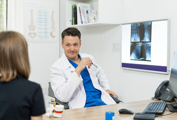 Obraz premium Doctor consulting a patient about X-ray results in a medical office. A doctor discusses X-ray results with a patient in a modern medical office setting