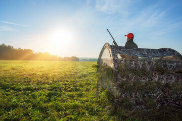 Hunter with shotgun in hunting blind during a hunt. Autumn season hunt.