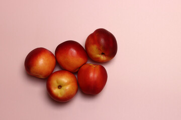 Ripe nectarines on a pink background with copy space. Flat lay, top view of fresh fruit on a table. Healthy eating concept. 
