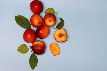 Ripe red nectarines on a blue background with leaves. Eating fresh concept. 