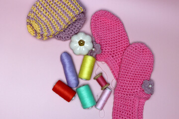 knitted clothes and accessories for needlework on a pink background.