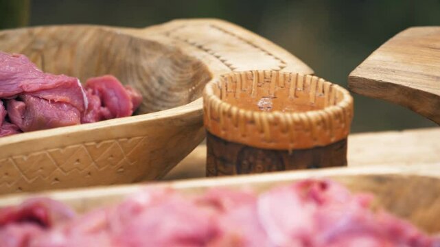 Closeup of mixing raw meat by hand in a wooden bowl. Craft culture of the Baltics. Historical reenactment. Rumsiskes, Lithuania- 07 05 2024. 