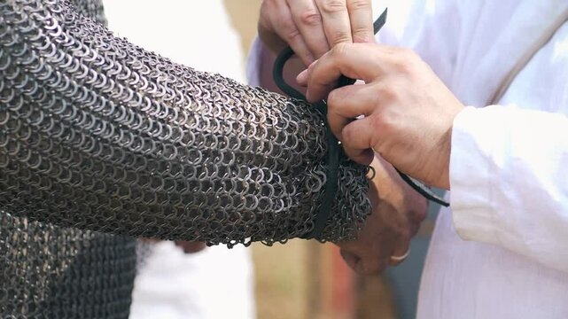 Preparing a soldier for battle. Chain tunic armor is put on. Historical reenactment close up. Rumsiskes, Lithuania- 07 05 2024. 