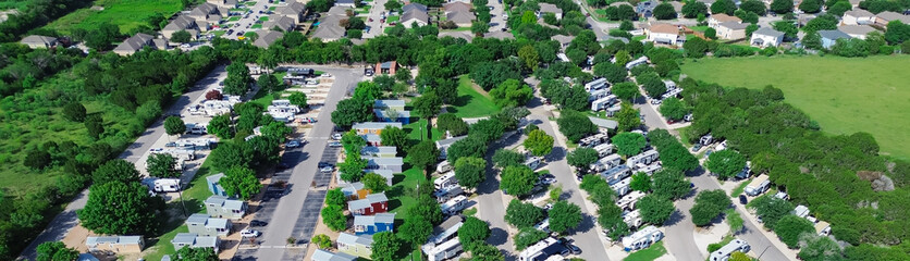 Panorama aerial view row of colorful cottage mobile home retreat vacation rentals, full hookup RV site in New Braunfels, Texas Hill Country, concrete pads electric service suburb San Antonio