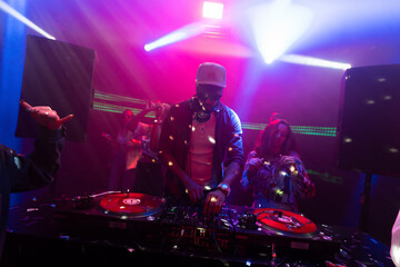 Happy people dancing hard with DJ. They are dancing with raised hands at a nightclub
