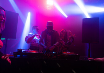 A crowd of women dancing while DJ controlling music on turntable in the nightclub