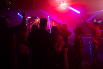 A crowd of people in disco dancing and clapping with Female DJ. Colorful flashes of light in...