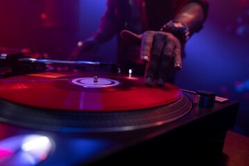 Hip hop dj scratching vinyl record on turntables against a black background in night club....