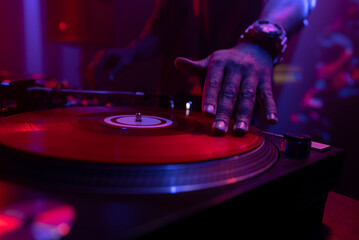 DJ spinning and scratching vinyl records, mixing music on turntable in a night club party....